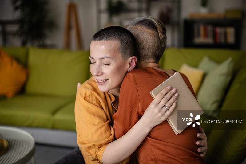 朋友在家中探望女性肿瘤患者，提供情感支持和陪伴，帮助她恢复。图片素材