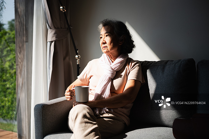 一位老年女性坐在那里发呆，显得很沮丧。图片素材