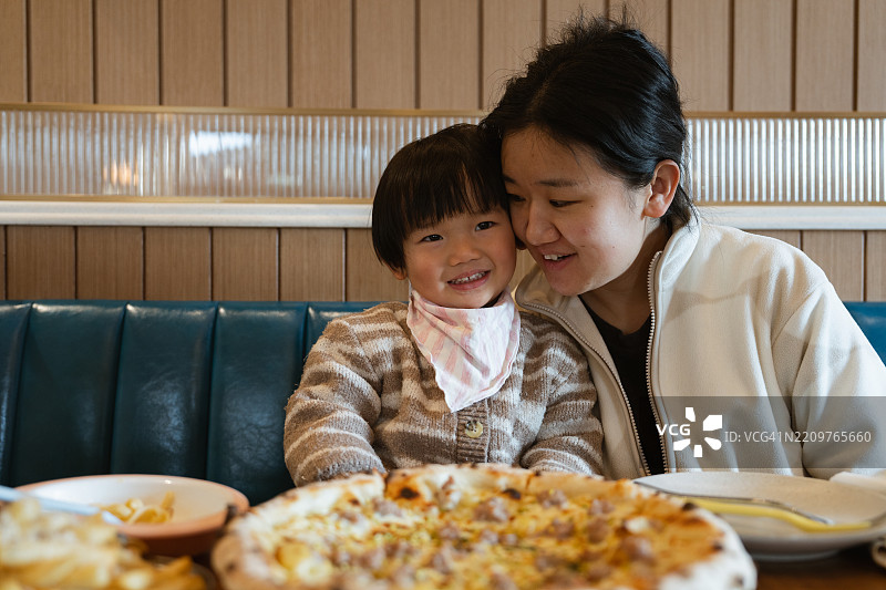 母女在餐厅一起享受比萨。图片素材