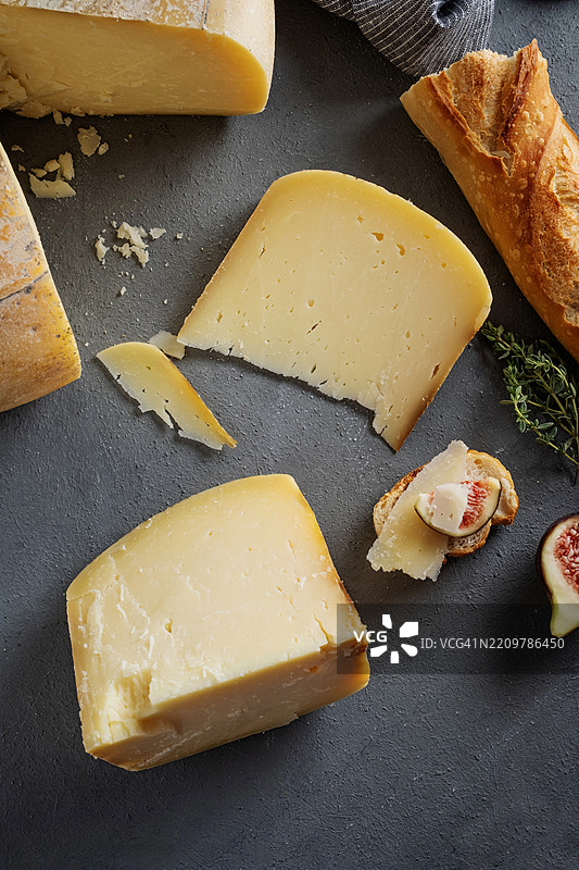 老卡萨尔奶酪轮。奶酪轮。手工奶酪。搭配面包和无花果的奶酪轮。深蓝色背景上的整轮奶酪。整轮奶酪上切去一块的样子。图片素材