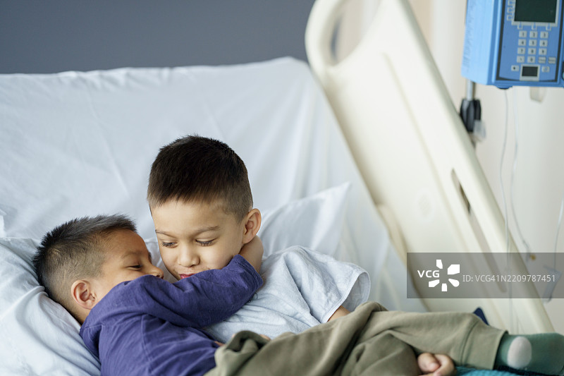 两个年轻男孩在医院病床上分享感人的时刻图片素材