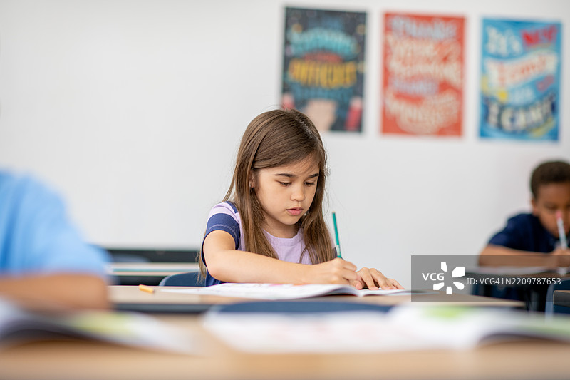 专注的学生在教室里用书本和笔学习图片素材