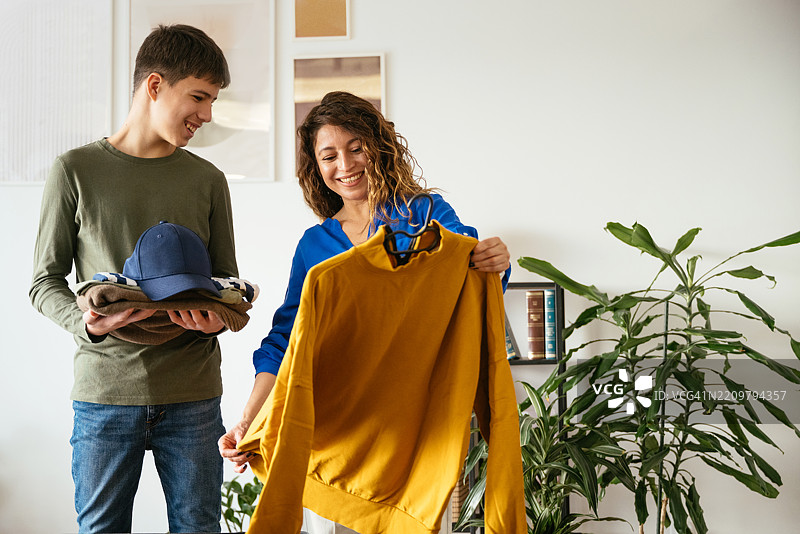 单身拉丁裔母亲与青少年男孩一起打包行李，准备旅行图片素材
