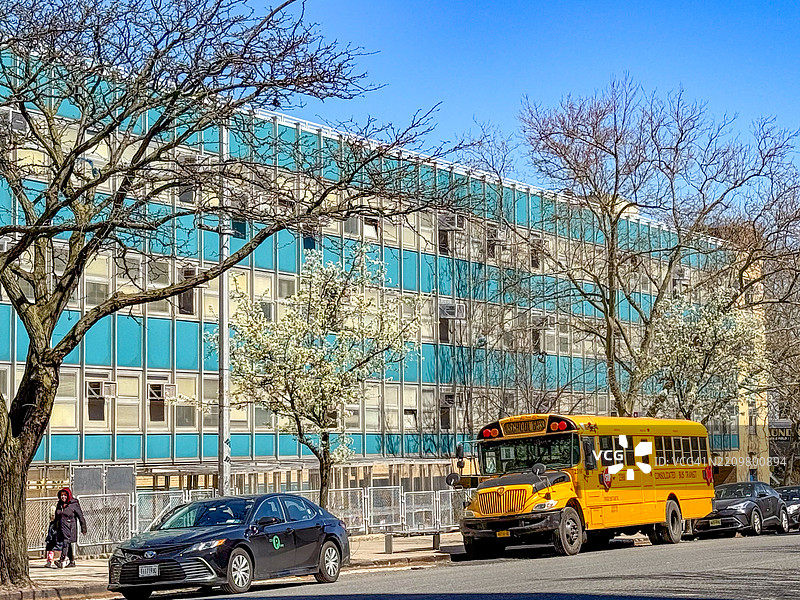 华盛顿高地，纽约市的28号公立学校，外面停着一辆黄色校车。图片素材
