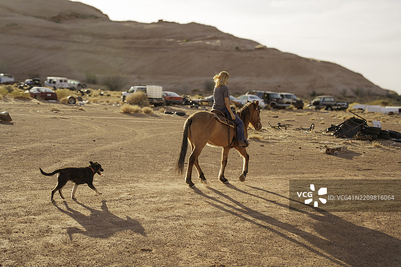 美丽的纳瓦霍女孩骑马在亚利桑那州的纪念碑谷附近的沙漠中图片素材
