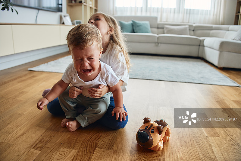 小男孩在哭泣，而他的姐姐在烦他。图片素材