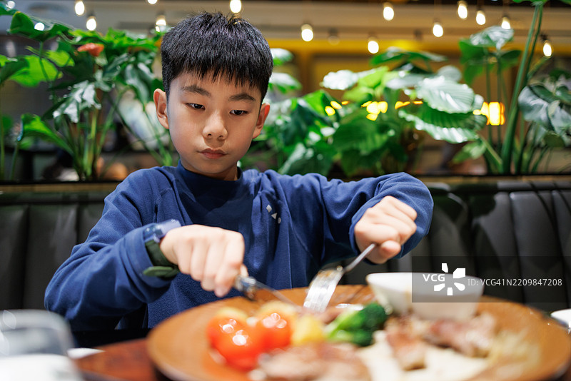 一个小男孩在餐厅里吃西餐图片素材
