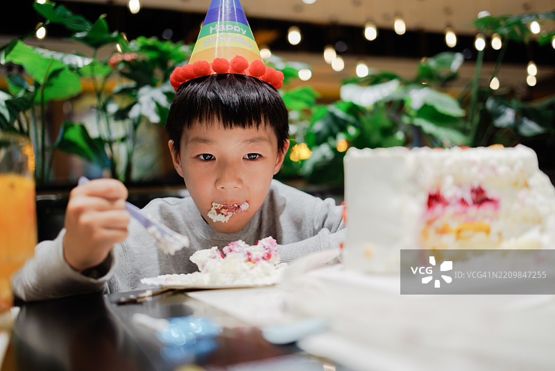 一个小男孩在餐厅里吃生日蛋糕图片素材