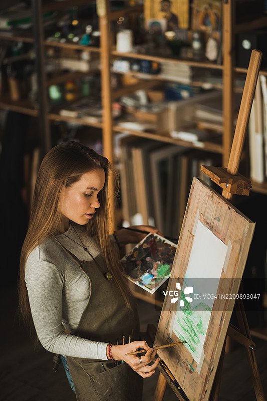 专注的女性艺术家在艺术工作室中绘画画布图片素材