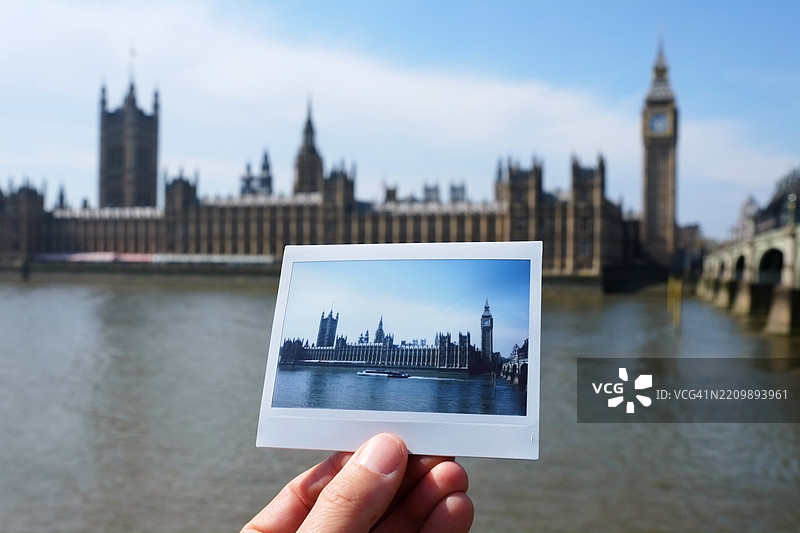 男子在伦敦威斯敏斯特宫前手持即时胶卷照片图片素材