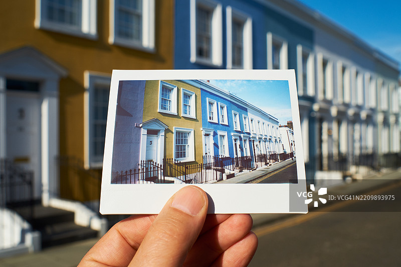 男子在伦敦一排联排别墅前手持即时胶卷照片图片素材