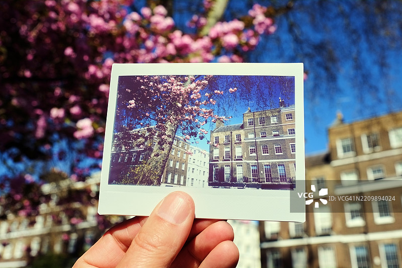 男子在伦敦一排联排别墅前手持即时胶卷照片图片素材
