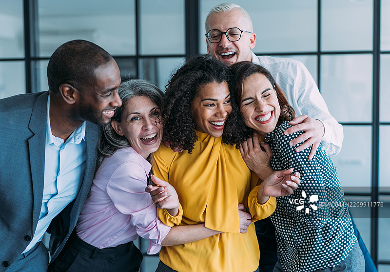兴奋的同事们在办公室庆祝时互相拥抱。图片素材