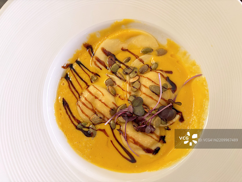 南瓜饺子配南瓜浓汤、焦黄油、南瓜子和陈年香醋图片素材