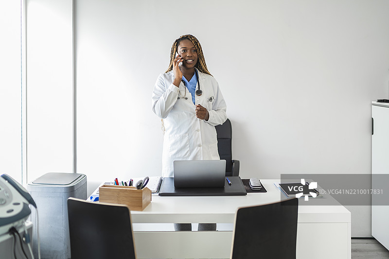 微笑的非裔美国医生在医疗办公室里打电话图片素材