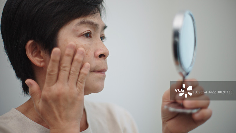 担忧的成熟的女性在关注皮肤问题。图片素材