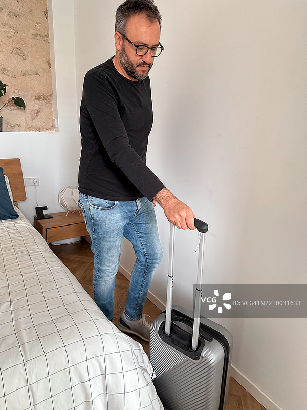 在家打包：男人带着行李箱离开房间图片素材