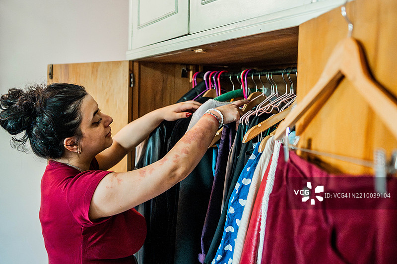 年轻女性在家中衣柜里挑选衣服图片素材