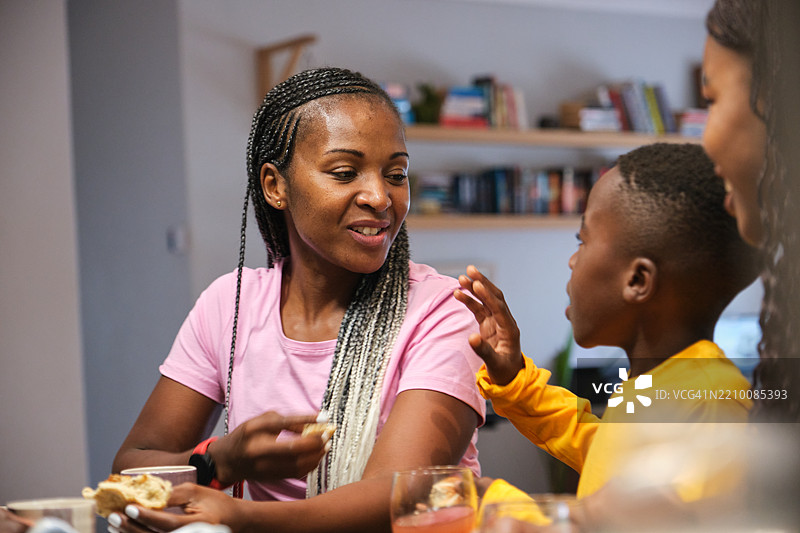 母亲在明亮现代的厨房里与她的小孩一起享受早餐图片素材
