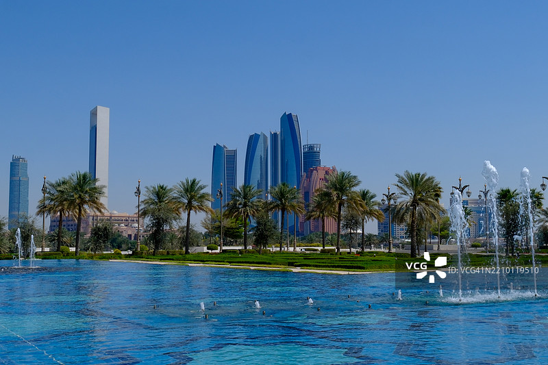 城市天际线前的喷泉，背景是阿布扎比的摩天大楼图片素材
