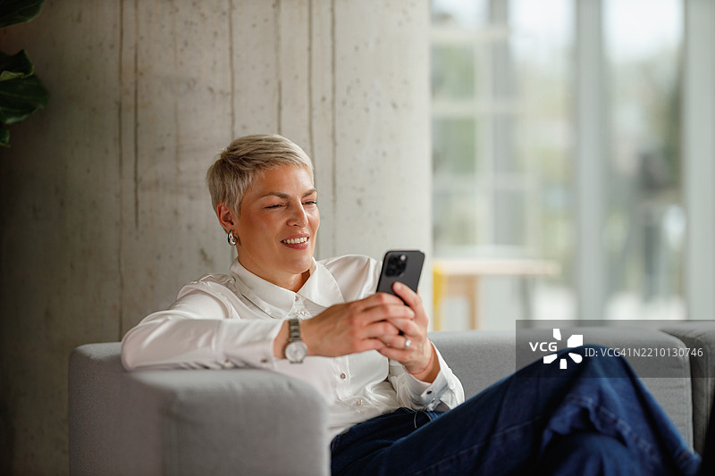 放松的女商人使用智能手机图片素材