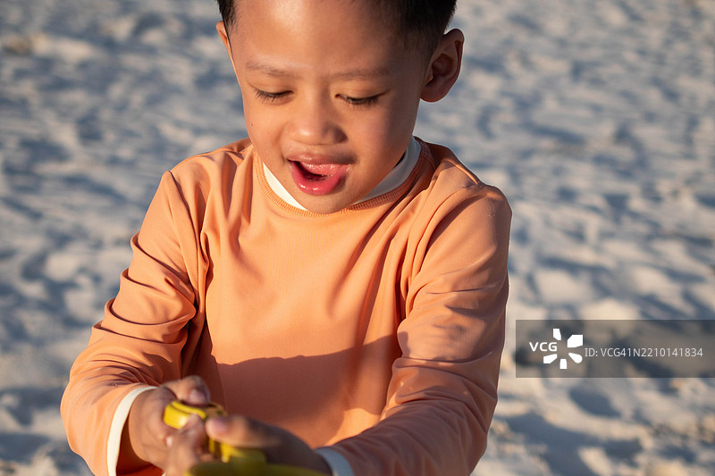 一个东南亚男孩在户外的海滩上玩耍图片素材
