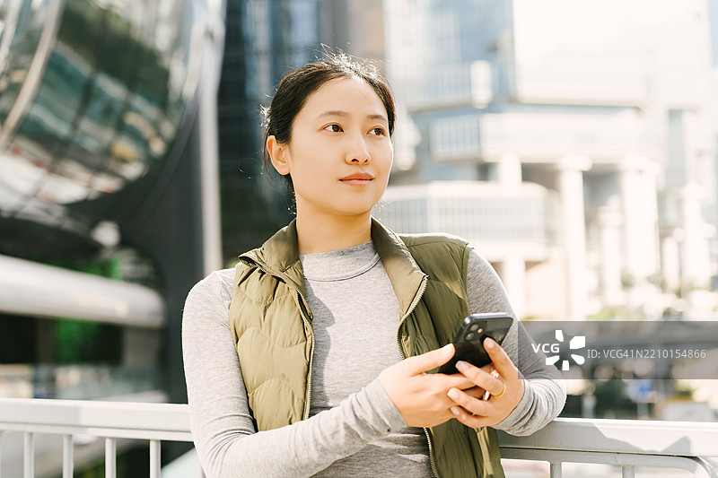现代女性白领在CBD的户外天桥上使用智能手机。现代商业客户服务。图片素材