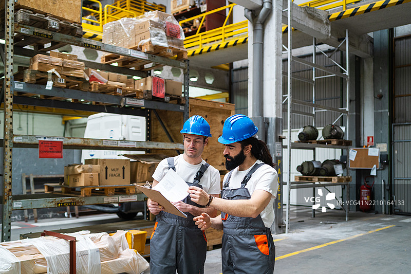 仓库工人使用夹板核对库存，跟踪工业制造设施中的库存水平图片素材