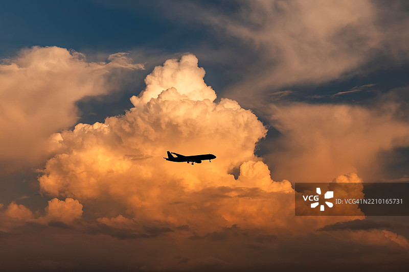 日落时分，飞机在雷雨云的背景下飞行图片素材