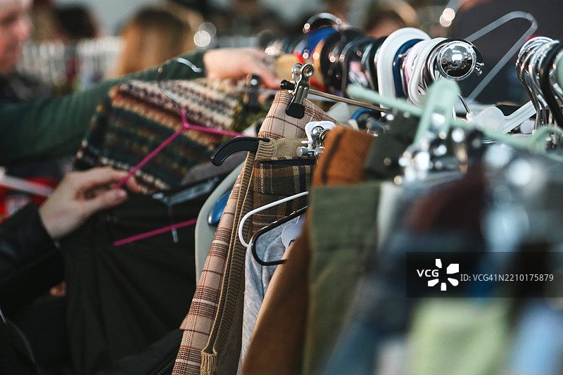 二手市场，衣架上挂着五彩斑斓的牛仔裤、裤子和毛衣。图片素材