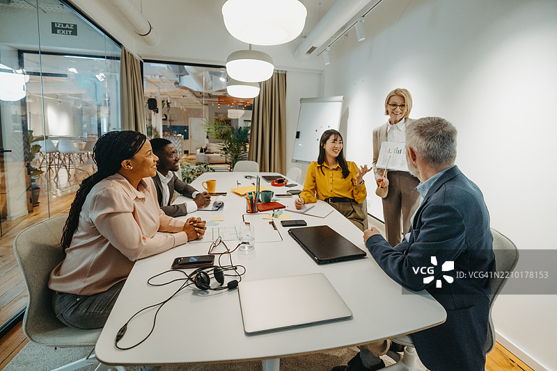 的女商人与同事在办公室会议室的桌子旁讨论图片素材