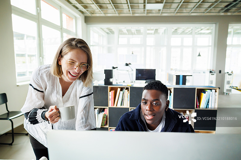 一个多元化的团队热情地合作，正在屏幕上审查一个项目。图片素材