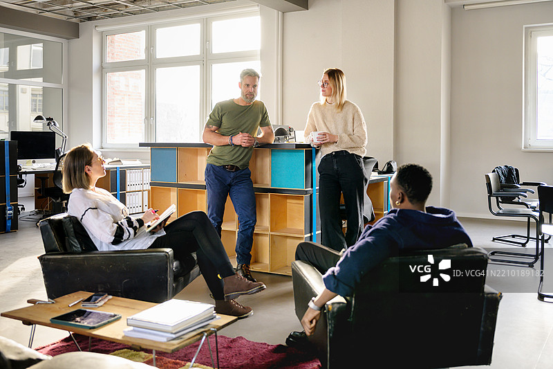 在一个充满创意和阳光的办公室区域，正在进行一场非正式的团队讨论。图片素材