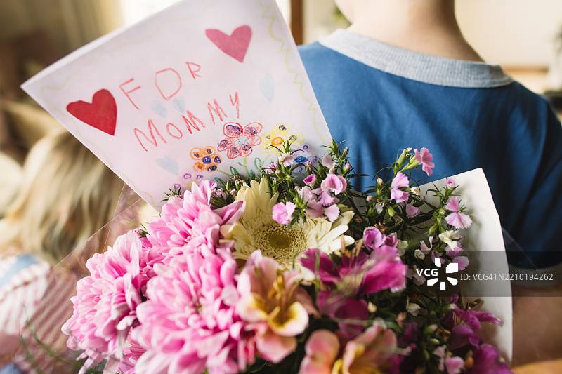 小男孩和小女孩手捧鲜花和贺卡，献给母亲图片素材