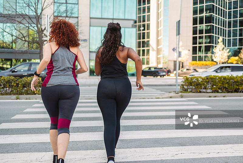 两位年轻女性在城市中奔跑图片素材