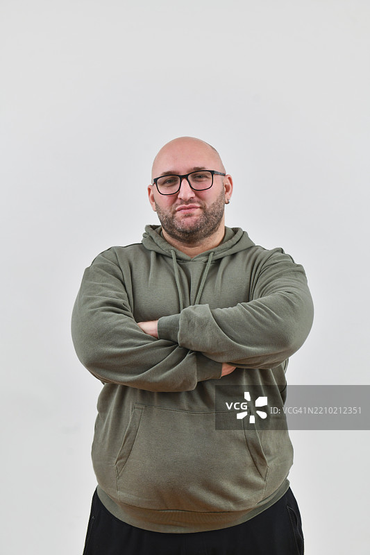 自信的男性双手交叉于胸前，站在白色背景前注视着镜头。图片素材