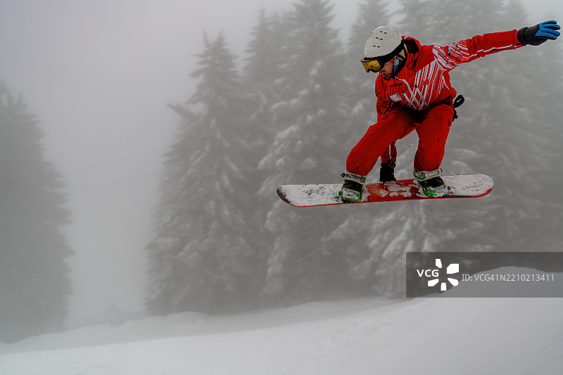 滑雪者在雪白的森林背景下空中跳跃图片素材