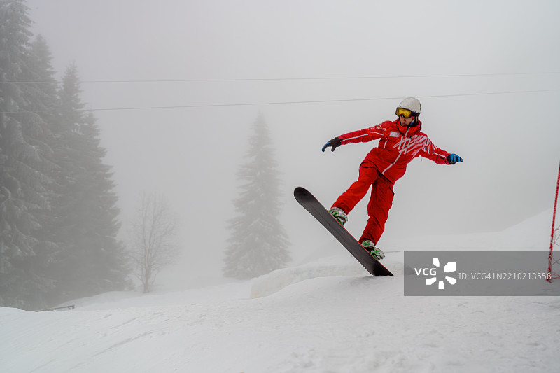 滑雪者在雾蒙蒙的冬日里在雪坡上跳跃图片素材