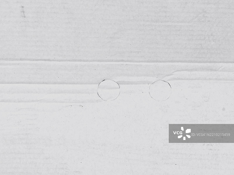 褶皱的白色纸板特写，带有两个圆圈。阳光。黑白色调。法国巴黎。图片素材