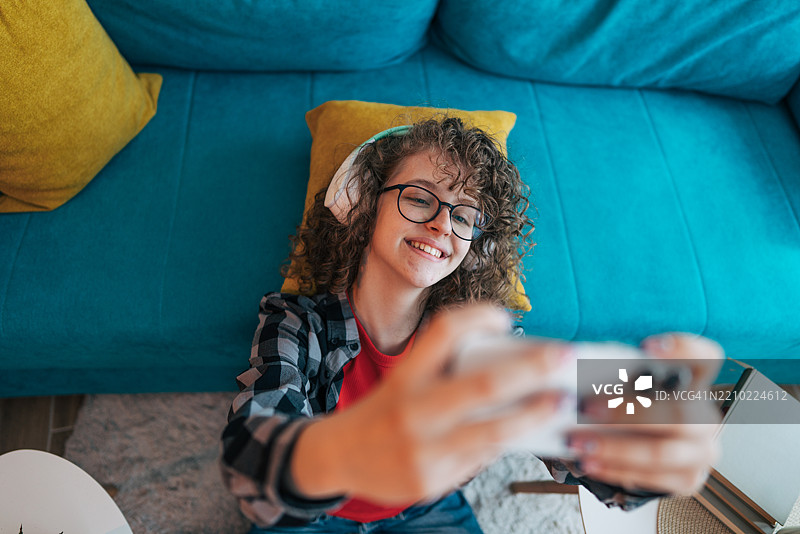 躺在地板上的少女用智能手机自拍图片素材