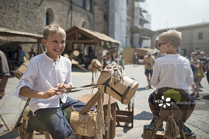 小男孩们在沃尔泰拉传统节日上享受玩具马旋转木马的乐趣图片素材