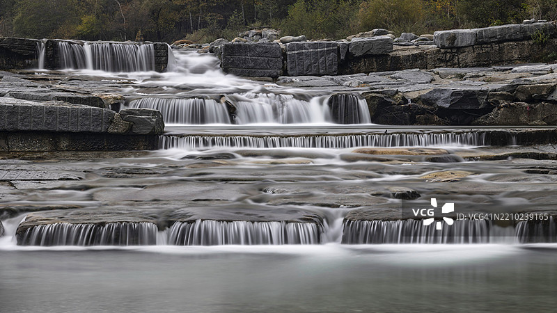 在意大利皮埃蒙特大区的瓦尔多索拉，令人印象深刻的多层瀑布在宁静的自然环境中流过石头。图片素材