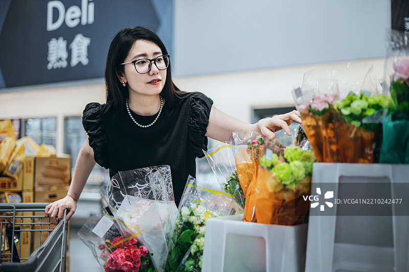 一位亚洲女性在超市挑选花卉图片素材
