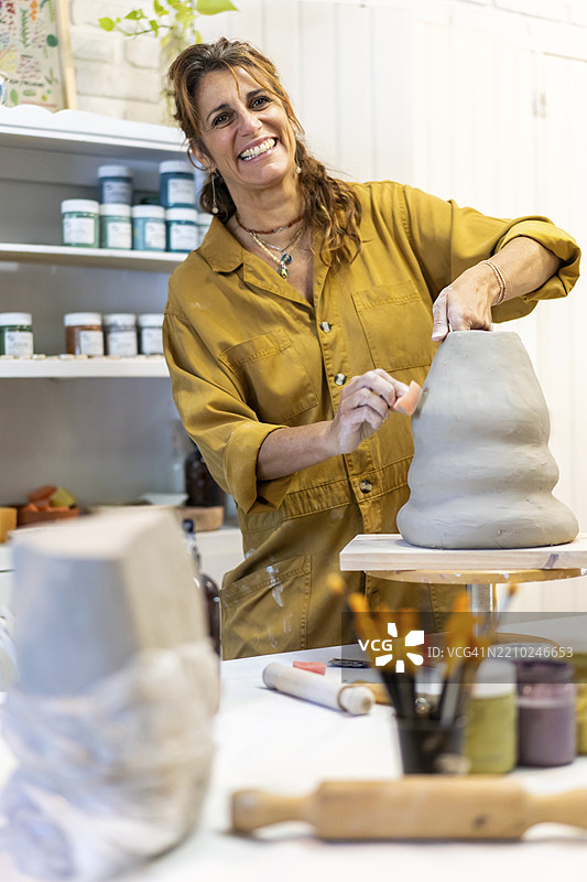 快乐的艺术家在充满活力的工作空间中捏制粘土图片素材