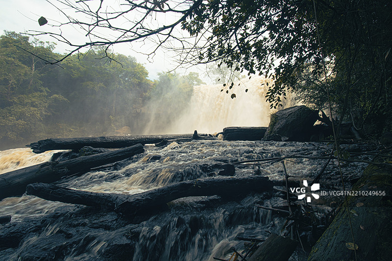 阴郁的森林场景，Bou Sra瀑布的水流在树木间穿梭，雾气弥漫在阴云密布的天空下。柬埔寨，蒙多基里省，亚洲图片素材