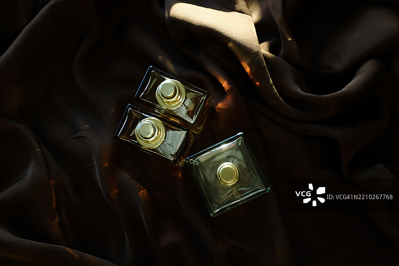 三个香水瓶，在柔和的阳光下。图片素材