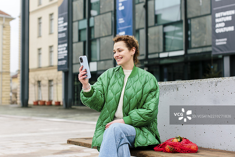 一位穿着绿色夹克的千禧女性在市中心休息图片素材