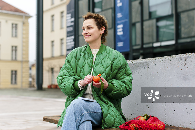 一位穿着绿色夹克的千禧女性在市中心休息图片素材