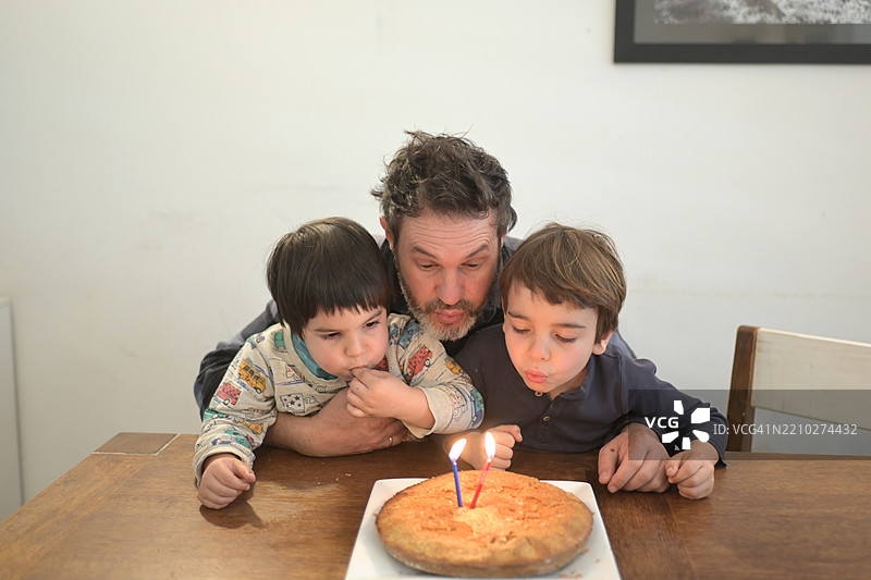 父亲和孩子们在蛋糕上吹蜡烛图片素材