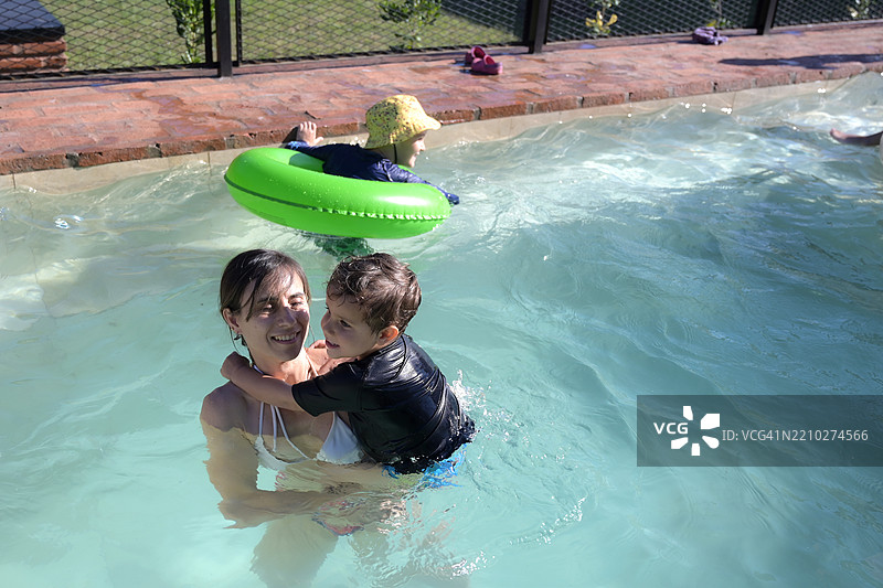 母亲在游泳池里和侄子们玩耍图片素材